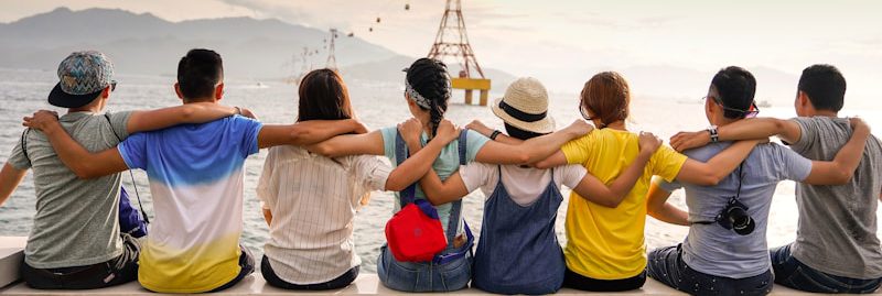 people holding shoulders sitting on wall