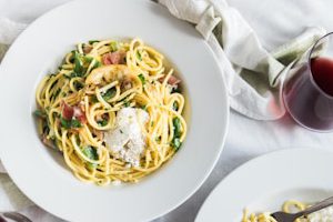 three round white plates with pasta near two glass cuups