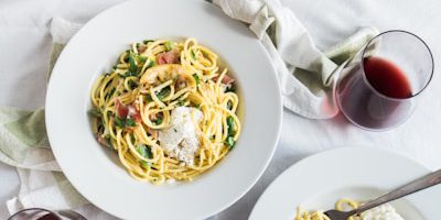 three round white plates with pasta near two glass cuups