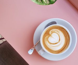 cup of coffee on saucer with teaspoon on pink tabletop