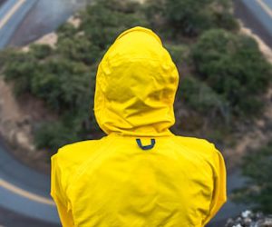 person in yellow coat standing on top of hill