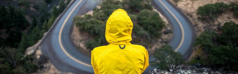 person in yellow coat standing on top of hill