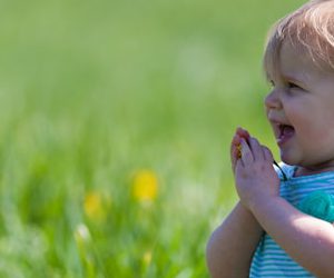 toddler with teal dress on green grass field during daytime