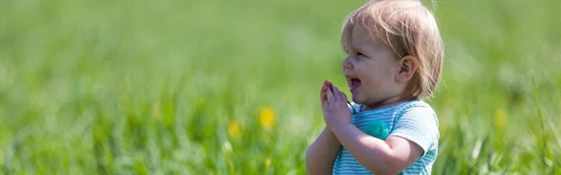 toddler with teal dress on green grass field during daytime