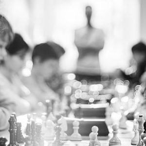 grayscale photography of children sitting while playing chess