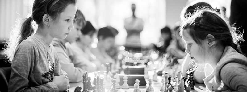 grayscale photography of children sitting while playing chess